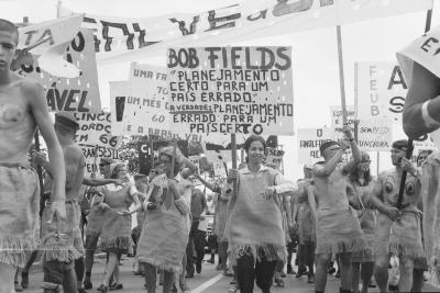 Calouros com roupa de estopa desfilam pela avenida W3 segurando cartazes como parte do trote da Universidade de Brasília
