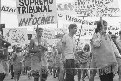 Calouros com roupa de estopa desfilam pela avenida W3 segurando cartazes como parte do trote da Universidade de Brasília