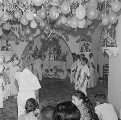 Festa de Cosme e Damião em Centro de Umbanda, ao fundo, Erivelto Martins (abaixado)