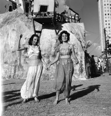 Mulheres fantasiadas em frente a uma decoração de rua no carnaval carioca