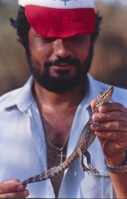 Homem não identificado com filhote de jacaré nas mãos