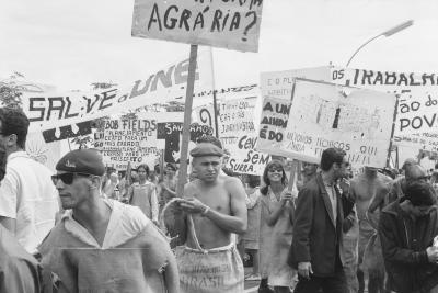 Calouros com roupa de estopa desfilam pela avenida W3 segurando cartazes como parte do trote da Universidade de Brasília