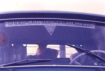 Janela de caminhão com a frase "Sofrendo pelas estradas pensando em quem deixei"