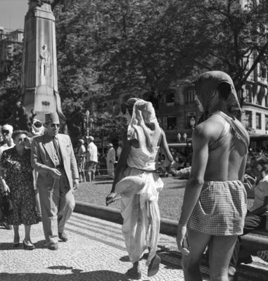 Carnaval de rua, homens fantasiados de mulher. Ao fundo, monumento a Floriano Peixoto