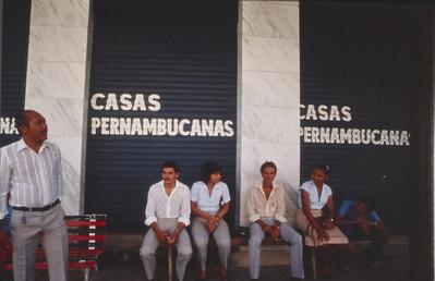 Pessoas sentadas em frente as Casas Pernambucanas