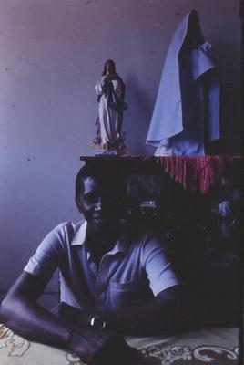 Homem não identificado, ao fundo escultura religiosa