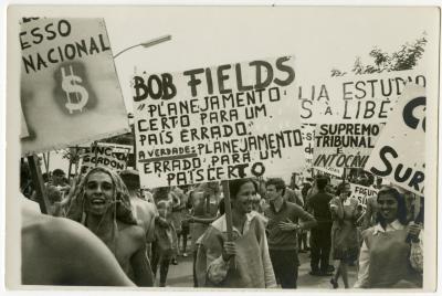 Calouros com roupa de estopa desfilam pela avenida W3 segurando cartazes como parte do trote da Universidade de Brasília