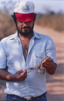 Homem não identificado com filhote de jacaré nas mãos