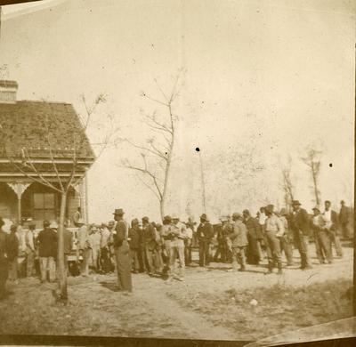 Grupo de homens em frente a uma casa