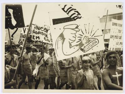 Calouros com roupa de estopa desfilam pela avenida W3 segurando cartazes como parte do trote da Universidade de Brasília
