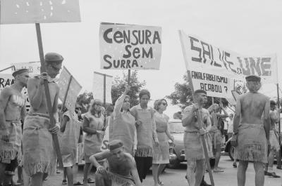 Calouros com roupa de estopa desfilam pela avenida W3 segurando cartazes como parte do trote da Universidade de Brasília