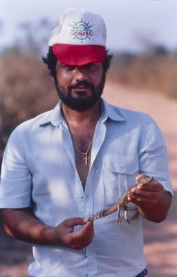 Homem não identificado com filhote de jacaré nas mãos