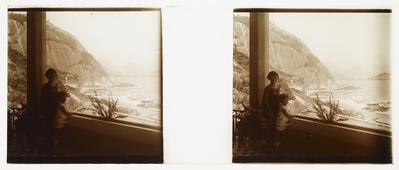 Criança em frente à janela, com vista para o mar