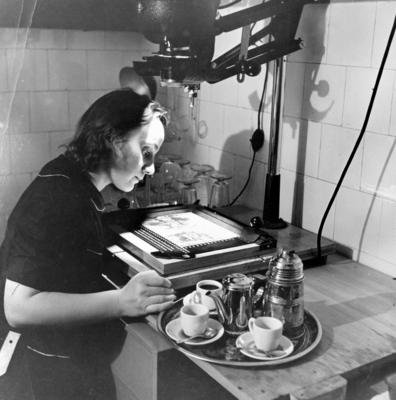 Hildegard Rosenthal trabalhando no ampliador, ao lado de bandeja de café
